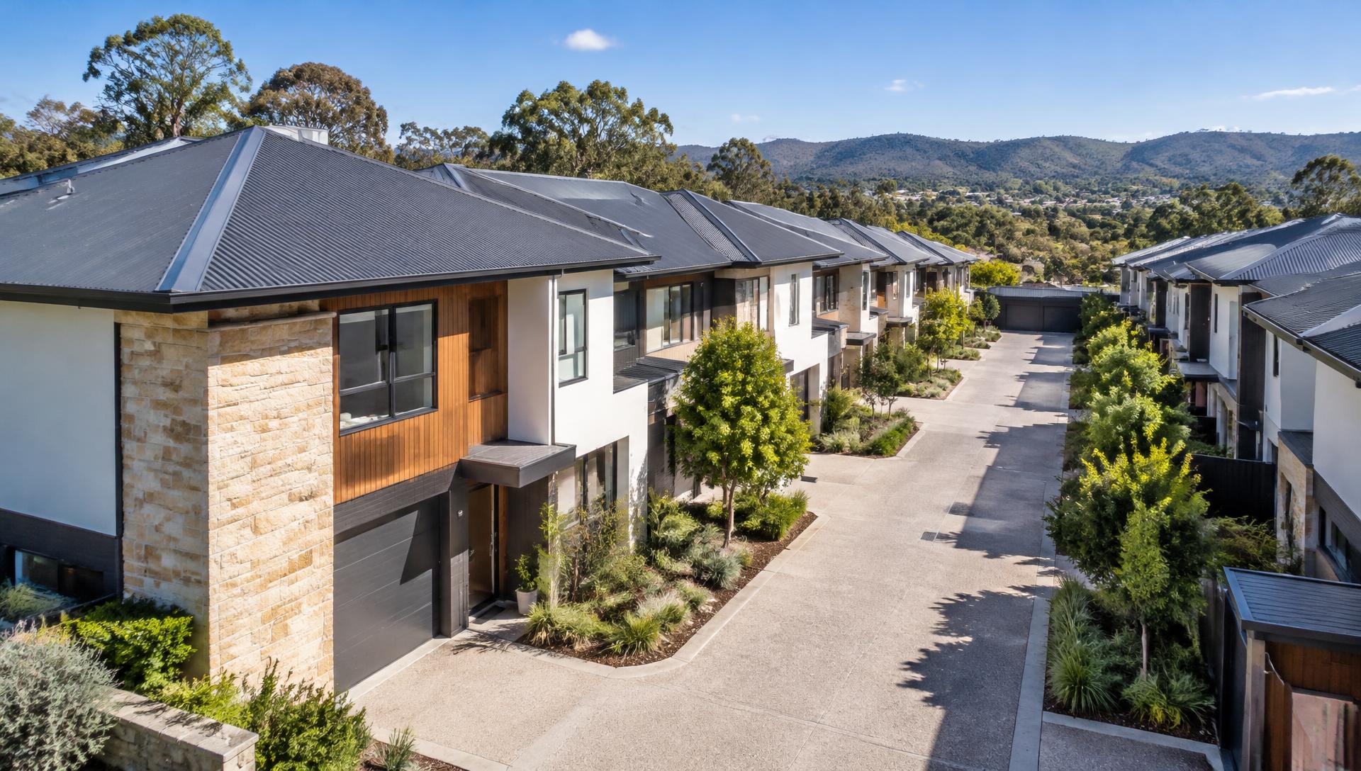 Well-kept modern townhouse complex with dark metal roofs and clean gutters