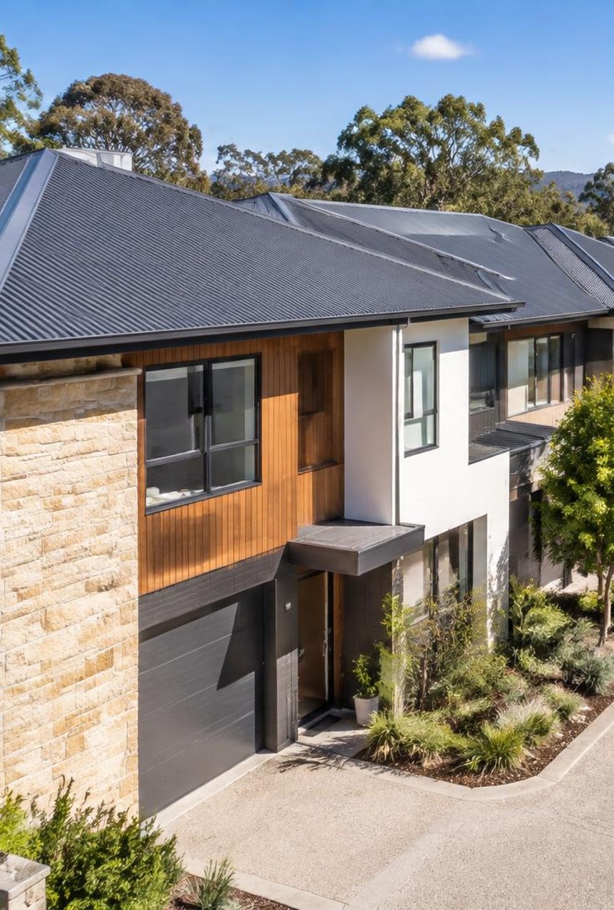 Well-kept modern townhouse complex with dark metal roofs and clean gutters